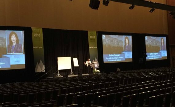 Barbara Rozgonyi delivering a keynote speech on LinkedIn strategy at the MDRT Annual Conference in Vancouver, speaking to a global audience in a 1,500-seat ballroom.